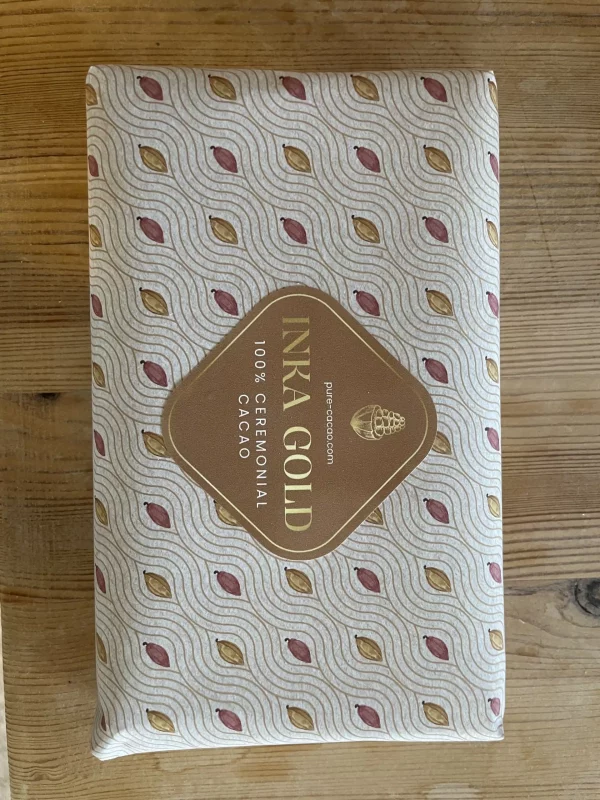 500g Inka Gold ceremonial cacao block wrapped in patterned paper featuring stylized cacao pod designs.