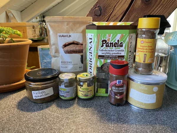 A selection of spices and superfoods for ceremonial cacao – including panela, reishi powder, clove, cinnamon, chipotle, and vanilla.