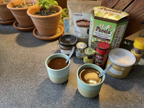 Two ceremonial cacao drinks in handcrafted ceramic cups, surrounded by natural sweeteners, spices, and superfood ingredients.