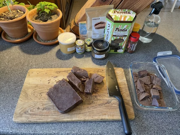 Second stage of chopping a 1kg ceremonial cacao block – large chunks cut and being transferred into a storage container.